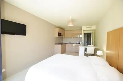 a bedroom with a white bed and a kitchen at La Perle d'Eze - Aparthotel in Èze