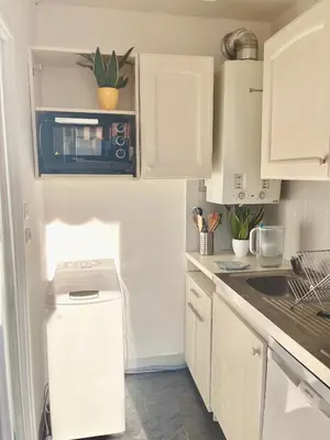 a kitchen with white cabinets and a washer and dryer at Studio with terrace and sea view, 10 min to the beach in Nice