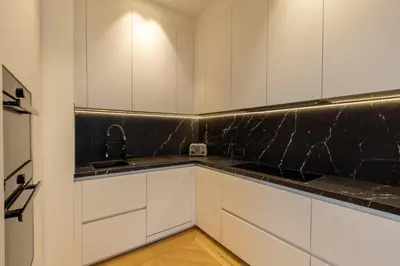a kitchen with white cabinets and a black counter top at QUAI PROMENADE New Seafront Balcony Air Conditioning in Nice