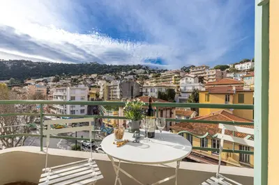 a balcony with a table and chairs and a city at FEEL HOME - DE GAULLE - Villefranche-sur-Mer in Villefranche-sur-Mer