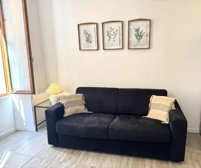 a black couch in a living room with three pictures on the wall at ApartHotel Riviera - Barillerie 12 - Vieille Ville 1mn plage - Appartement 2 pieces AC in Nice