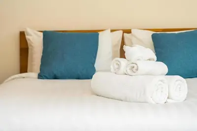 a pile of towels on a bed with blue pillows at ApartHotel Riviera - ISTRIA 1- Old town Promenade des Anglais - Superbe Appartement Superior 2 Pièces AC in Nice