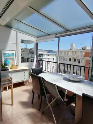 a large room with a table and chairs on a balcony at Nice Vue Mer 50m plage Parking in Nice