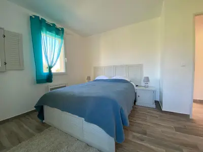 a bedroom with a bed with a blue blanket and a window at Villa Flora in La Gaude