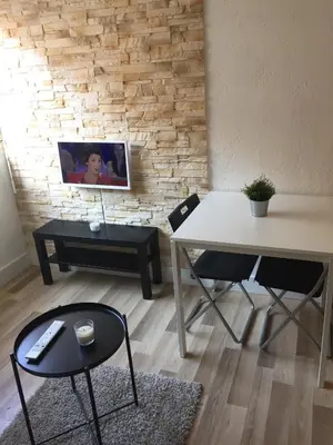 a living room with a table and chairs and a tv at Studio à 2 pas de la promenade des anglais in Nice