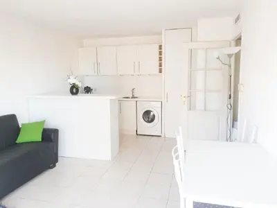 a living room with a black couch and a kitchen at Résidence Les domes, Piscine in Nice