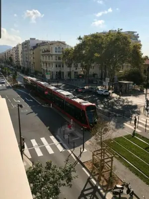 a red train on a street in a city at Résidence Les domes, Piscine in Nice