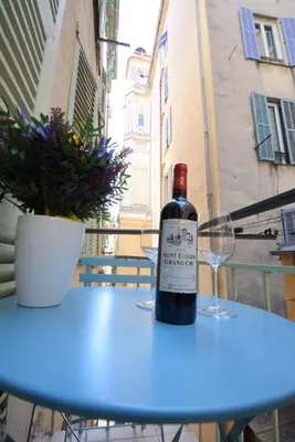 a bottle of wine sitting on a table with glasses at Nice Renting - PAIROLIERE - SPACIOUS FLAT - OLD NICE - MASSENA - TERRACE in Nice