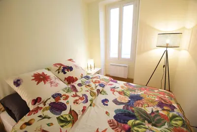 a bedroom with a bed with a flowered blanket and a window at Nice Renting - PAIROLIERE - SPACIOUS FLAT - OLD NICE - MASSENA - TERRACE in Nice