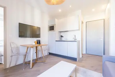 a living room with a table and a kitchen at 2 BAVASTRO - Beau 2 pieces lumineux et cosy - Climatise in Nice