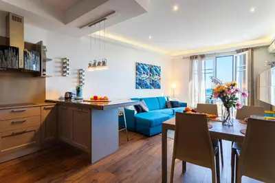 a kitchen and living room with a blue couch at BAMBOO PLAGE AP4220 by Riviera Holiday Homes in Nice