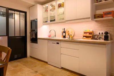 a kitchen with white cabinets and a black refrigerator at Magnifique appartement au centre-ville de Nice in Nice