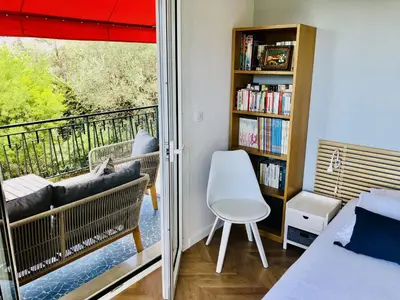 a bedroom with a balcony with a bed and a book shelf at Beautiful T3 terrasse Nice in Nice