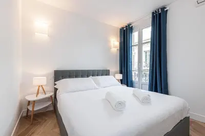 a bedroom with a large white bed with blue curtains at ChezDudi in Nice