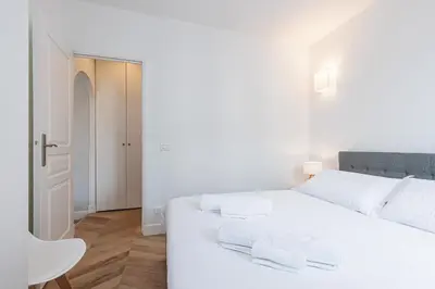 a white bedroom with a white bed and a chair at ChezDudi in Nice