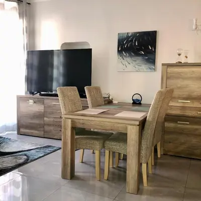 a dining room table with chairs and a flat screen tv at CHARMING APARTMENT NEAR THE BEACH in Villefranche-sur-Mer