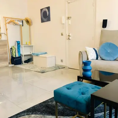 a living room with a couch and a blue ottoman at CHARMING APARTMENT NEAR THE BEACH in Villefranche-sur-Mer