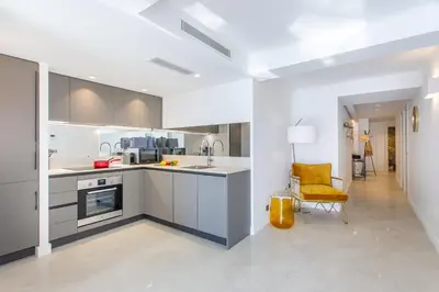 a kitchen with white cabinets and a yellow chair at I love Nice - FACE MER, DESIGN, TERRASSE, ASC, WIFI, CLIM in Nice