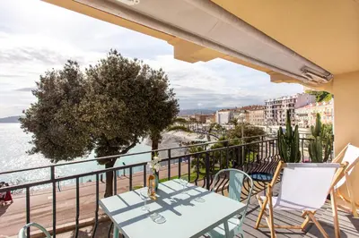 a balcony with a table and chairs and a view of the ocean at I love Nice - FACE MER, DESIGN, TERRASSE, ASC, WIFI, CLIM in Nice