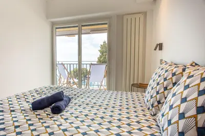 a bedroom with a bed with a view of a balcony at I love Nice - FACE MER, DESIGN, TERRASSE, ASC, WIFI, CLIM in Nice