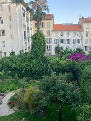 a garden in front of a building with trees and bushes at Nice Centre: à 300m de la mer et de la Promenade des Anglais in Nice