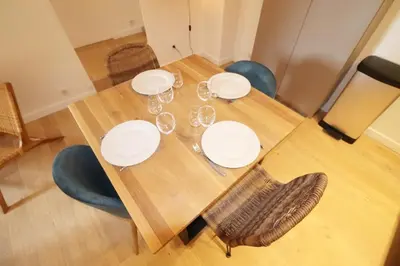 a wooden table with white plates and wine glasses at Superbe Appartement au coeur de la vieille ville in Villefranche-sur-Mer