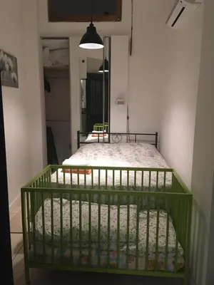 a green crib in a room with a bedroom at Cozy house with parking and garden in Nice