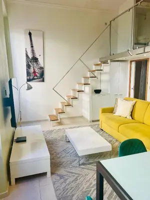 a living room with a yellow couch and stairs at Alexandre Mari old town few meters to the beach in Nice