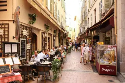 a group of people sitting at tables on a city street at Beautiful Old Town flat, near the beach in Nice