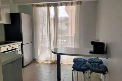 a kitchen with a table and stools in front of a window at Grand Studio avec Coin Nuit et Parking in Saint-Laurent-du-Var