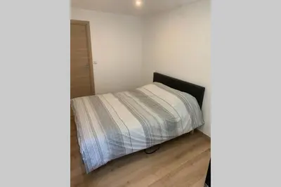a small bedroom with a bed with a striped blanket at Appartement neuf 4-6 personnes en bord de Mer in Nice