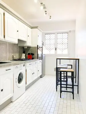 a white kitchen with a washing machine and a table at Résidence Le Castille in Nice