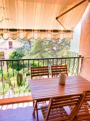 a wooden table and chairs on a balcony with a view at Résidence Le Castille in Nice