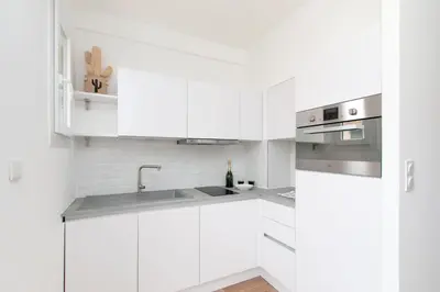 a white kitchen with white cabinets and a sink at Maison Bianchi - Herold in Nice