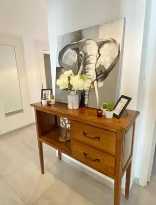 a wooden dresser with flowers and a painting on it at Le Philanthrope - Balcon Wifi Climatisation in Nice