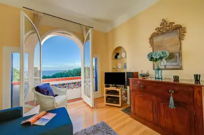 a living room with a tv and a balcony at Villa MonTLilin - Happy Rentals in Villefranche-sur-Mer