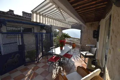 a patio with a table and chairs on a balcony at Studio climatisé et sa terrasse privée en villa in La Trinité