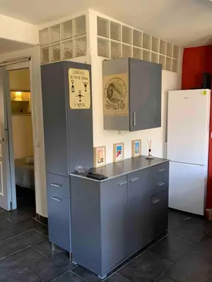 a kitchen with gray cabinets and a white refrigerator at Cosy sweet space in paradise - 5min from the beach in Nice