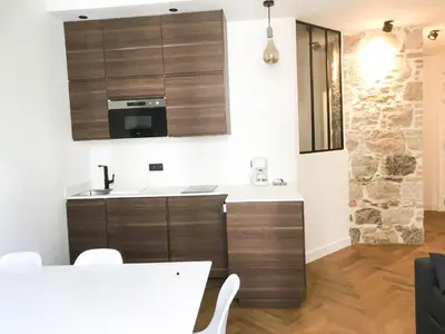 a kitchen with wooden cabinets and a white counter top at Buffa Résidence in Nice