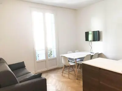 a living room with a table and chairs and a couch at Buffa Résidence in Nice