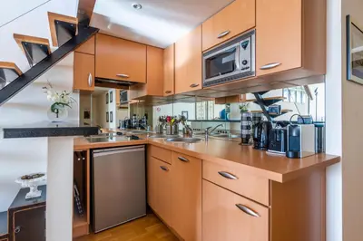 a kitchen with wooden cabinets and a microwave at Samourai Massena Lodge -1 min from the sea in Nice