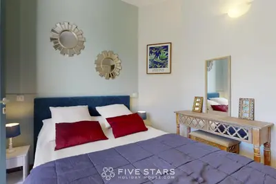 a bedroom with a bed with red pillows and a mirror at Villa Capriciosa - Five Stars Holiday House in Beaulieu-sur-Mer