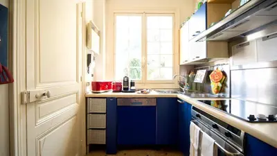 a kitchen with blue cabinets and a sink and a window at La NONETE in Villefranche-sur-Mer