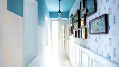 a hallway with blue walls and pictures on the wall at La NONETE in Villefranche-sur-Mer