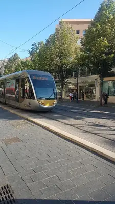 a train is traveling down a city street at NEW CHEAP PRIVATE ROOM, KITCHEN , OVERWIEUW sea,TRAM on spot, 12 minutes from nice train station with tram , beach in 17 min tram , CHAMBRE PRIVÉE pas cher, cuisine équipée , tram sur place, APERÇU mer, 12 min de la gare de Nice avec le tram, 17 min plage in Nice