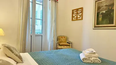 a bedroom with a bed and a chair and a window at ApartHotel Riviera - JEAN JAURES 1 - Vieille Ville - Appartement de 3 pieces AC - 100m de la plage in Nice