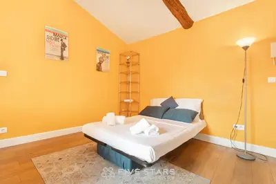 a bedroom with a large bed with yellow walls at Vieux Nice - Jean Jaurès FSHH in Nice