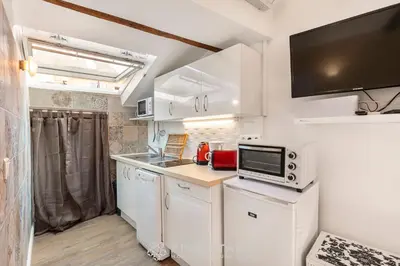a kitchen with white cabinets and a tv on the wall at Vieux Nice - Jean Jaurès FSHH in Nice