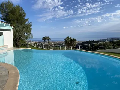 a large blue swimming pool with a view of the ocean at VILLA NICE-GAIRAUT by RIVIERA HOLIDAY HOMES in Nice