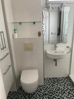 a white bathroom with a toilet and a sink at Studio vue mer in Beaulieu-sur-Mer